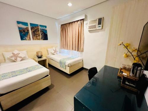 a hotel room with two beds and a desk at Treetop Suites in Coron