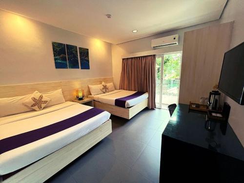 a hotel room with two beds and a television at Treetop Suites in Coron