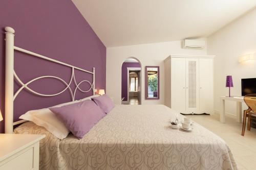 a bedroom with a large bed with purple walls at Hotel Residence Il Porto in Mattinata