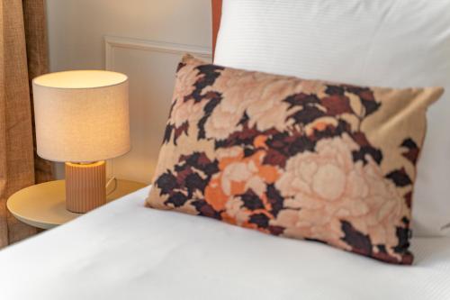 a pillow sitting on a bed next to a lamp at SHWAY - The Saffron Dress in Antwerp