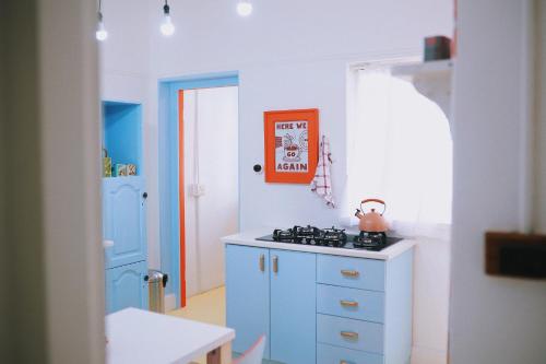 a kitchen with blue cabinets and an orange picture on the wall at Casamore in Mossel Bay