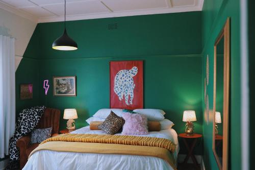 a bedroom with a green wall with a bed at HARBOUR VIEW FUNKY AND ECLECTIC TWO BEDROOM HOME in Mossel Bay