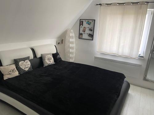 a bedroom with a black bed with pillows and a window at Otello vendegház in Szekszárd
