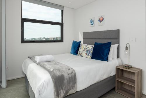 Un dormitorio con una cama grande con almohadas azules y una ventana en The Iron Works Apartments en Ciudad del Cabo