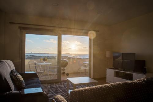 a living room with a couch and a television and a balcony at Best Houses 64 - Sunset Beach in Ferrel