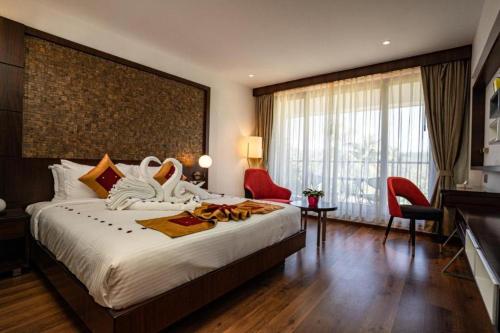 um quarto de hotel com uma cama grande e uma janela grande em Saugandhika West Gate em Wayanad