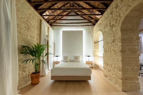 a bedroom with a white bed in a stone wall at La Posada Del Alma in Córdoba