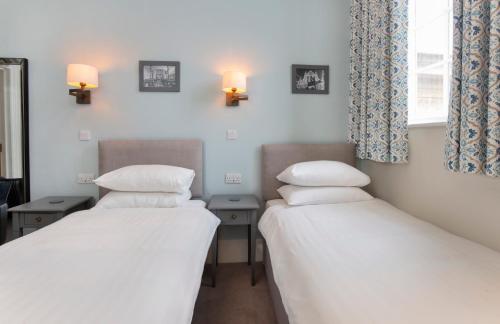 two beds in a room with two lamps on the wall at The Bar Convent Guest House in York