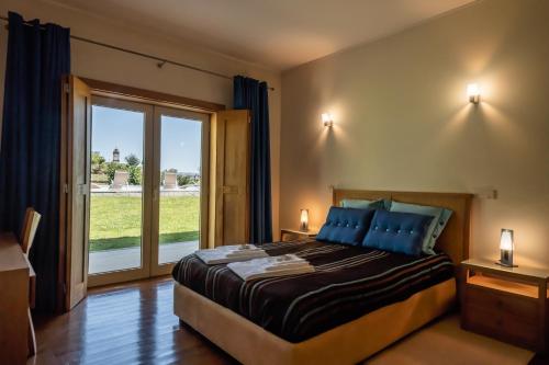 ein Schlafzimmer mit einem großen Bett und einem großen Fenster in der Unterkunft Matos Casas de Campo in Cabeceiras de Basto