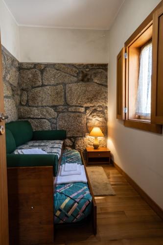 a bedroom with a green bed and a stone wall at Matos Casas de Campo in Cabeceiras de Basto