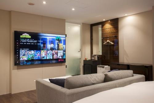 ein Wohnzimmer mit einem Sofa und einem Flachbild-TV in der Unterkunft P&F Hotel in Taichung