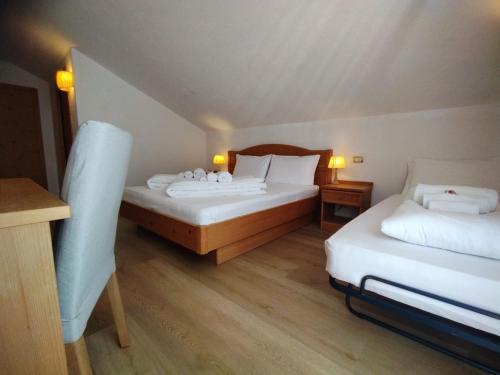 a hotel room with two beds and two tables at Hotel Grizzly in Folgaria