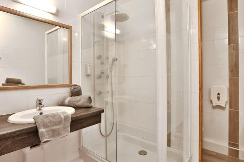 a bathroom with a sink and a shower at Hotel Restaurant Logis Le Tropicana in Douville