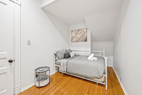 a white bedroom with a bed and a wooden floor at Lincoln Park Gem in Chicago