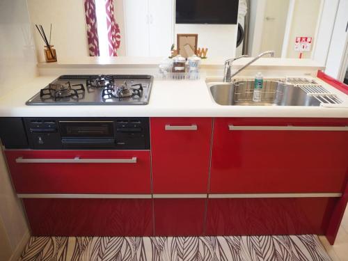 a kitchen with red cabinets and a stove and a sink at Harbour Inn & Suites 202 in Niigata
