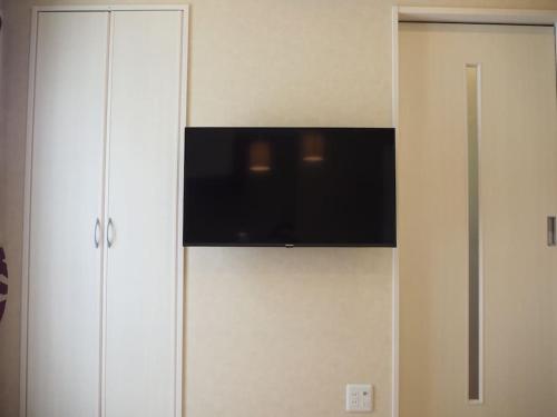 a flat screen tv on top of a white cabinet at Harbour Inn & Suites 202 in Niigata