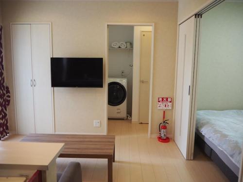 Sala de estar con cama y TV en la pared en Harbour Inn & Suites 202 en Niigata