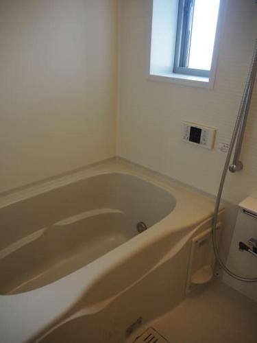 a white bath tub in a bathroom with a window at Harbour Inn & Suites 202 in Niigata