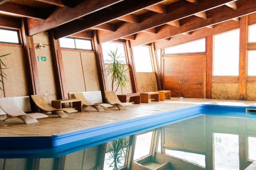 una casa con piscina y algunas sillas en MI Lodge Las Trancas Hotel & Spa, en Las Trancas