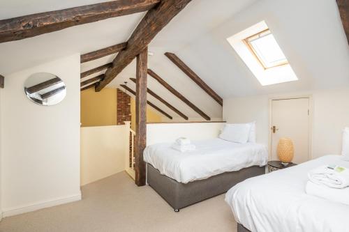 two beds in a attic bedroom with a skylight at Pass the Keys Charming Cottage near Clifton Moor in York