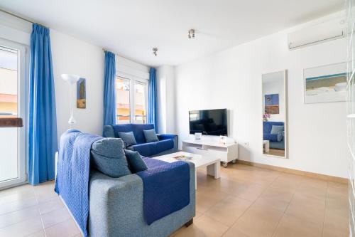 a living room with a blue couch and a tv at Apartamentos Delamar in Carboneras