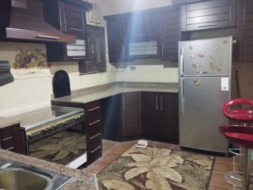Una cocina con refrigerador de acero inoxidable y gabinetes de madera. en apartment pyramids view, en Giza