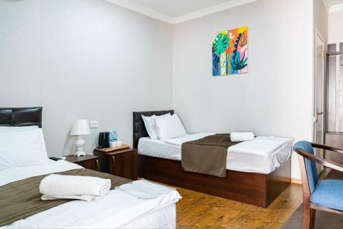 タシュケントにあるHotel & Hostel Galleryのベッド2台と椅子があるホテルの部屋