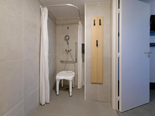 a bathroom with a shower and a stool in it at B&B HOTEL Le Mans Nord 2 in Saint-Saturnin