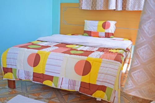 a bed with a colorful quilt on it in a room at TAITA LUXURY HOTELS LTD in Wundanyi