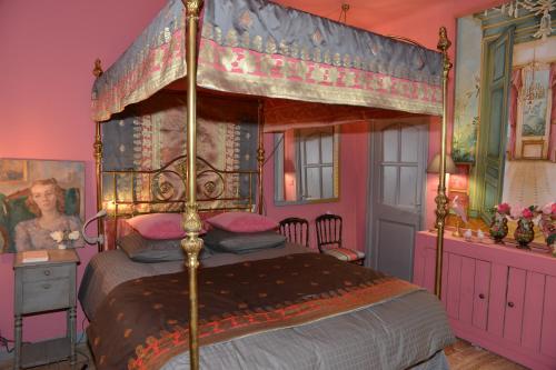 a bedroom with a canopy bed in a pink room at La BARBELLA in Lourmarin