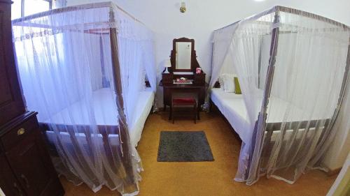a room with a bed and a dresser and a mirror at Fort Dew Guest House in Galle