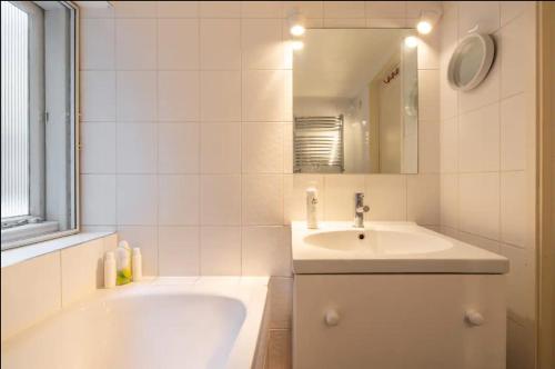 a white bathroom with a tub and a sink at Pass the Keys Cosy 1 bedroom flat in Knightsbridge in London