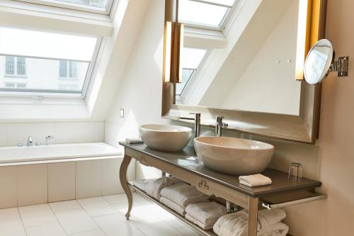 a bathroom with two sinks and a mirror at Steigenberger Hotel Herrenhof in Vienna