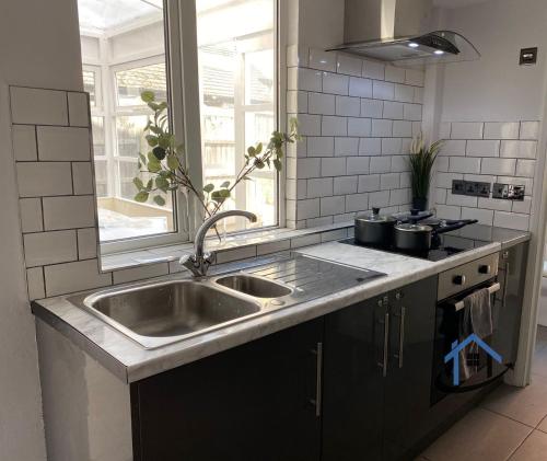 a kitchen with a stainless steel sink and a window at Acaster House, Rooms 1 to 5, free parking, SUPER fast wi-fi, en-suite, corporates welcome in Kettering