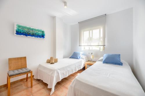 a bedroom with two beds and a chair at Edificio can Sord Apto nº 2 in La Savina