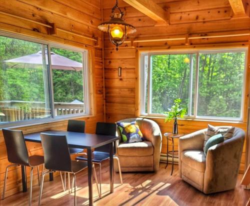 a dining room with a table and chairs and windows at Juniper Cabin- Waterfront retreat on Mosque Lake in Ompah