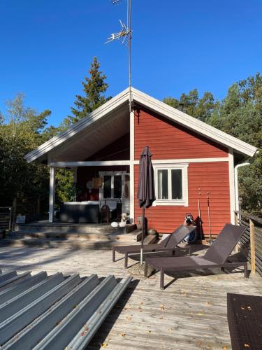 a red building with two lounge chairs and an umbrella at Charmigt hus på Vindö in Stockholm