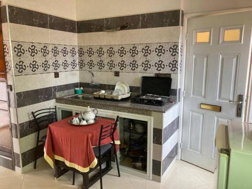a small kitchen with a table with a red table cloth at Joli studio au centre d'Agadir in Agadir