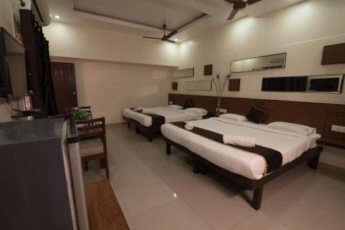 a room with three beds and a tv in it at Arunik Inn in Puducherry