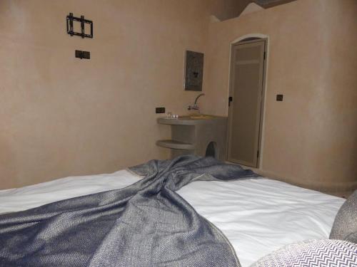 a bedroom with a bed and a bathroom with a sink at Dar Diafa Chez Anaam in Er Rachidia