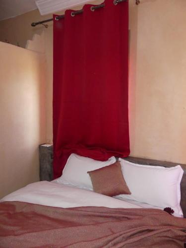a red curtain above a bed with white pillows at Dar Diafa Chez Anaam in Er Rachidia