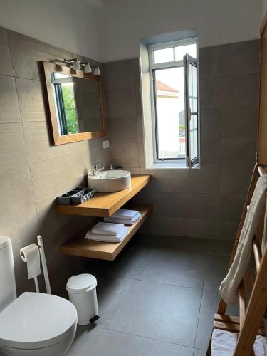 a bathroom with a sink and a toilet and a window at Casa do Avô in Ponta do Sol