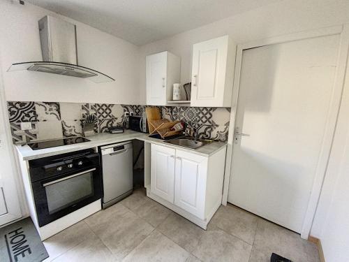 une cuisine avec des armoires blanches et un four à plaques de cuisson dans l'établissement T2 Centre ville avec jardin, à Arles