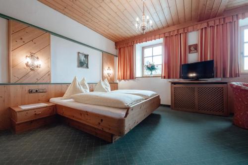 1 dormitorio con 1 cama y TV en Dandler - Zimmer und Ferienwohnungen, en Fieberbrunn
