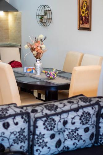 a dining room table with chairs and a vase of flowers at Apartman Petar Pan in Grude