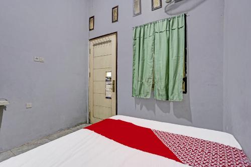 a bedroom with a red and white bed with a window at OYO 91795 Kos Jeehel Syariah in Sidoarjo