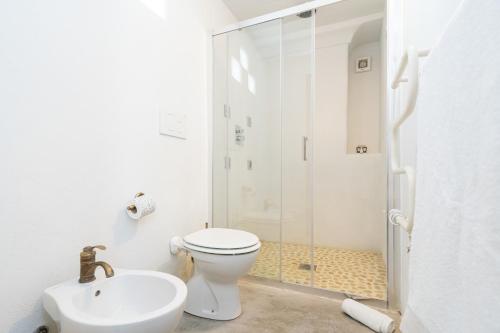 a white bathroom with a toilet and a shower at Tenuta del Barco WineRestaurant and Hospitality in Pulsano
