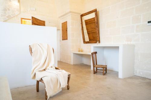 a white room with a chair and a mirror at Tenuta del Barco WineRestaurant and Hospitality in Pulsano