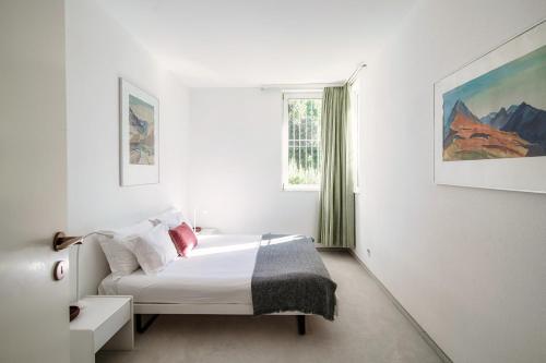 una camera bianca con un letto e una finestra di Evia Apartment - bright three-room apartment with lake view a Vernate