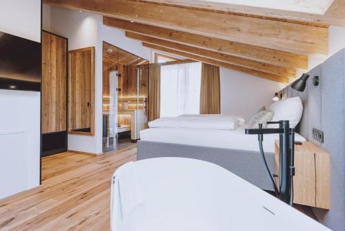 two beds in a room with wooden ceilings at ZAGLGUT HOTEL-CHALETS Wellness & Views with Summer Card Included in Kaprun
